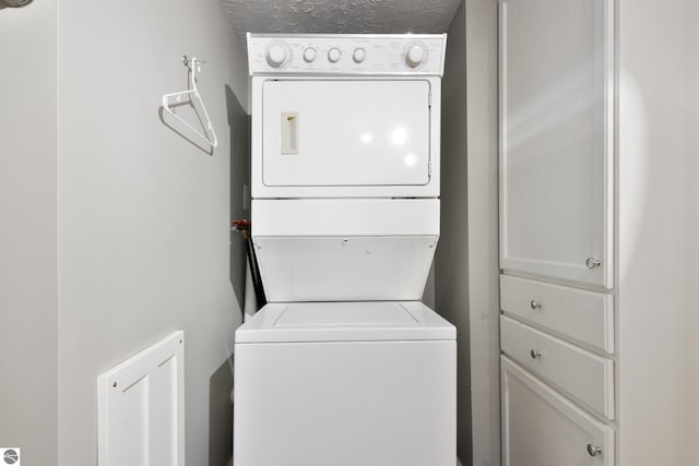 laundry room with stacked washing maching and dryer and a textured ceiling