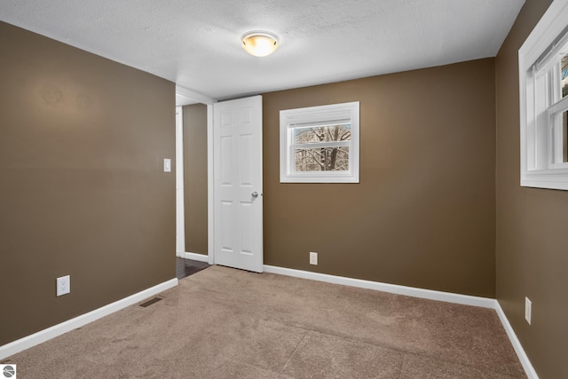 carpeted spare room featuring a textured ceiling