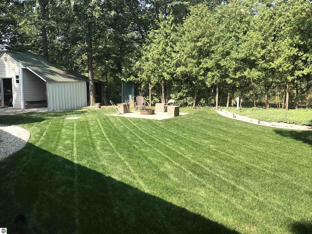 view of yard featuring a patio area, an outbuilding, and a fire pit