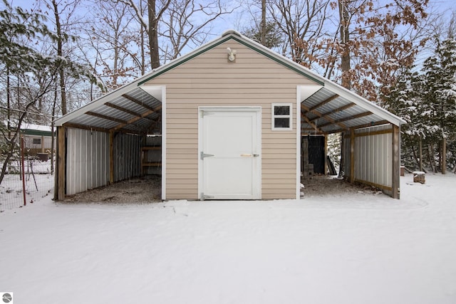 snow covered structure with a carport