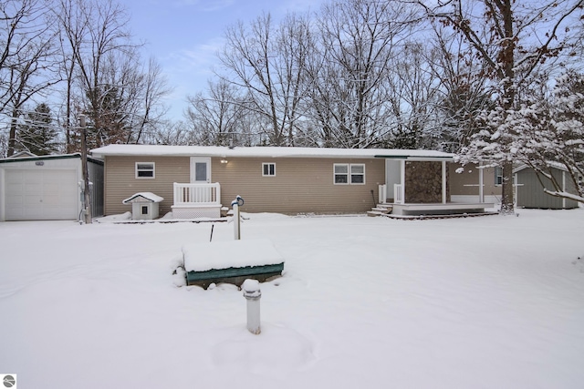 snow covered house featuring a garage and an outdoor structure