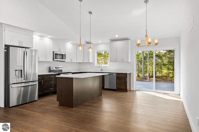 kitchen featuring a wealth of natural light, a center island, hanging light fixtures, stainless steel appliances, and white cabinets