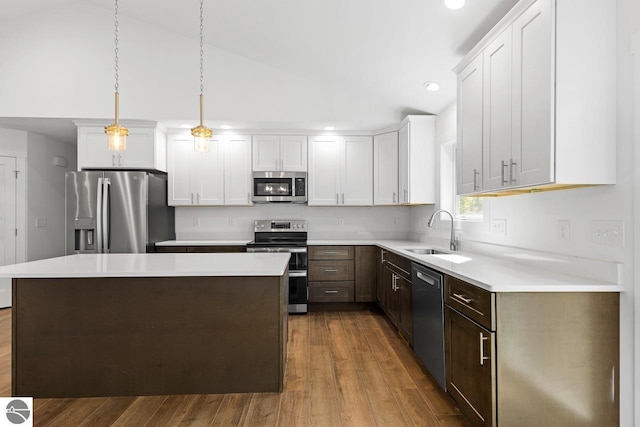 kitchen with a center island, white cabinets, sink, appliances with stainless steel finishes, and decorative light fixtures