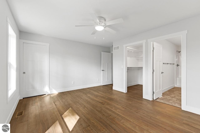 unfurnished bedroom featuring hardwood / wood-style floors, ceiling fan, a spacious closet, and a closet