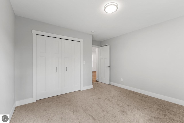 unfurnished bedroom featuring light carpet and a closet