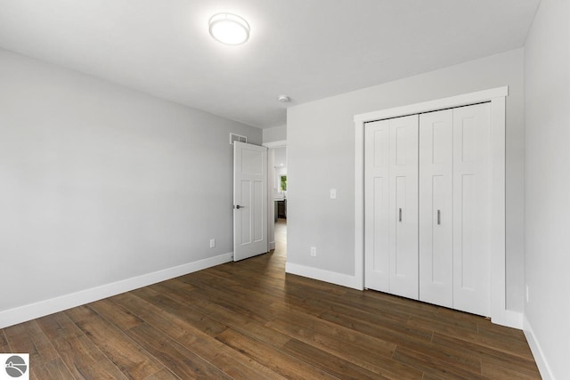 unfurnished bedroom with dark wood-type flooring and a closet