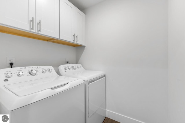 clothes washing area featuring washer and clothes dryer and cabinets