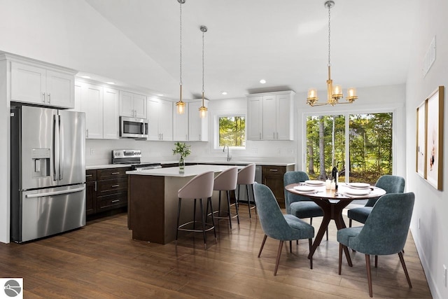 kitchen featuring white cabinets, appliances with stainless steel finishes, a center island, and pendant lighting