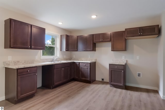 kitchen featuring dark brown cabinetry, sink, and light wood-type flooring