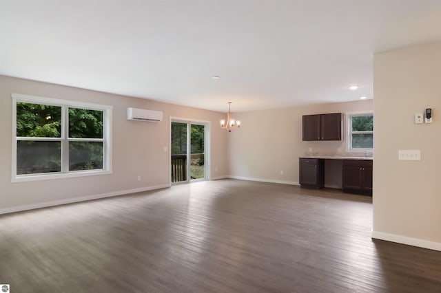 unfurnished living room featuring dark hardwood / wood-style flooring, a wall unit AC, and a chandelier