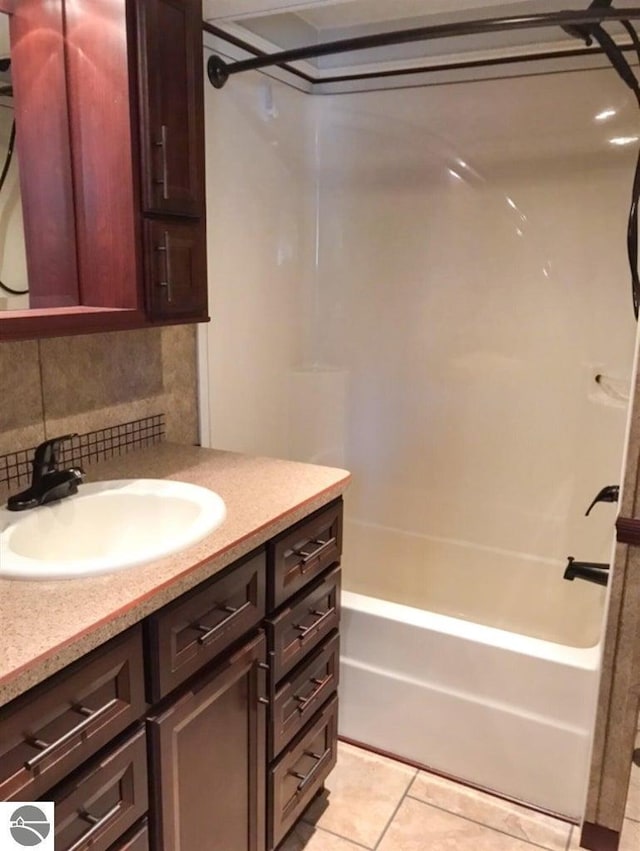 bathroom featuring tile patterned flooring, decorative backsplash, washtub / shower combination, and vanity