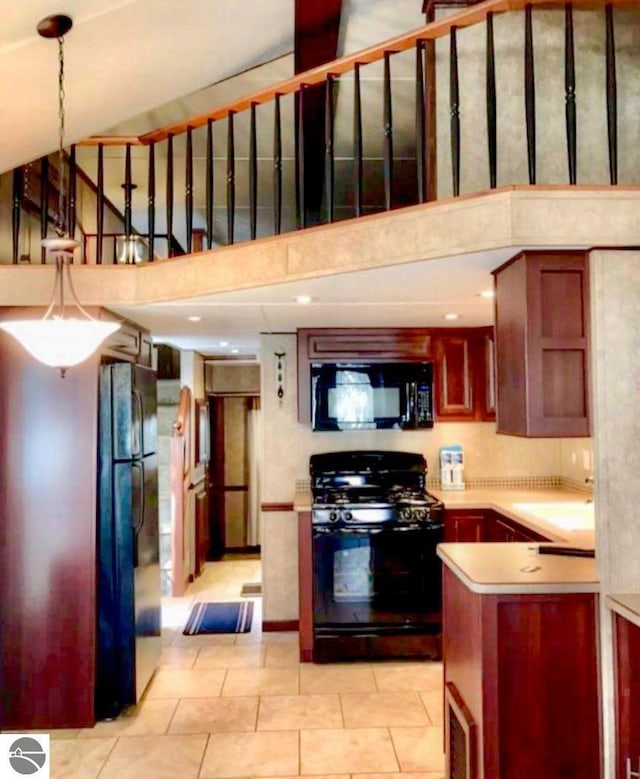 kitchen featuring kitchen peninsula, hanging light fixtures, a towering ceiling, and black appliances