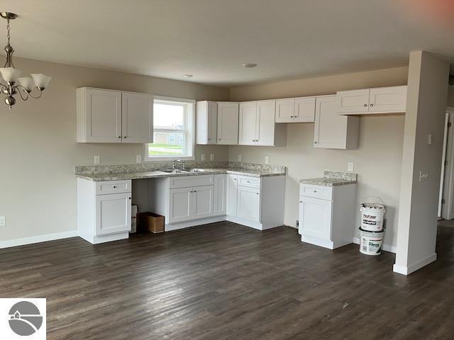 kitchen with white cabinets, decorative light fixtures, an inviting chandelier, and sink