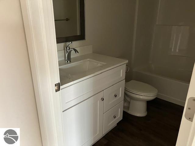 full bathroom with vanity, hardwood / wood-style flooring, toilet, and shower / bathtub combination