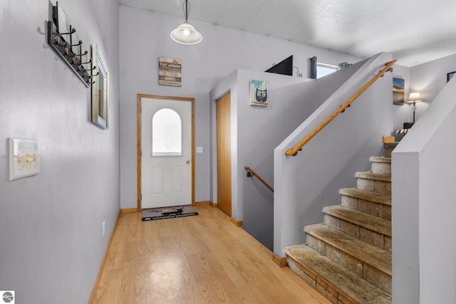 foyer featuring a wealth of natural light, hardwood / wood-style floors, a towering ceiling, and a textured ceiling