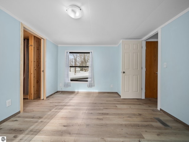 spare room featuring crown molding and light wood-type flooring