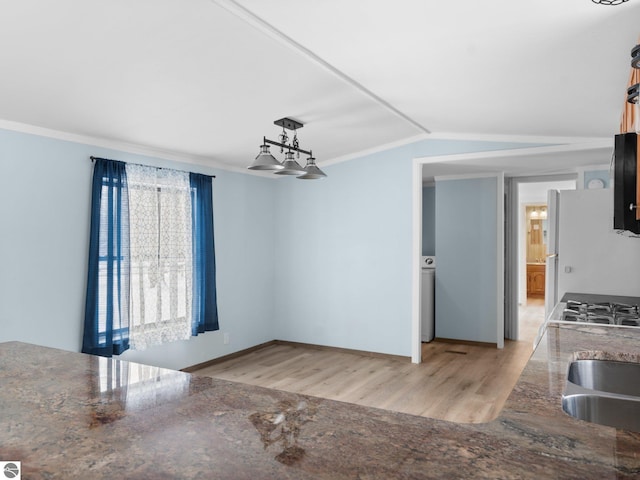 unfurnished dining area with light wood-type flooring, ornamental molding, sink, and vaulted ceiling