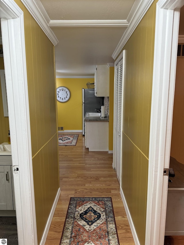 corridor with hardwood / wood-style floors, crown molding, and sink