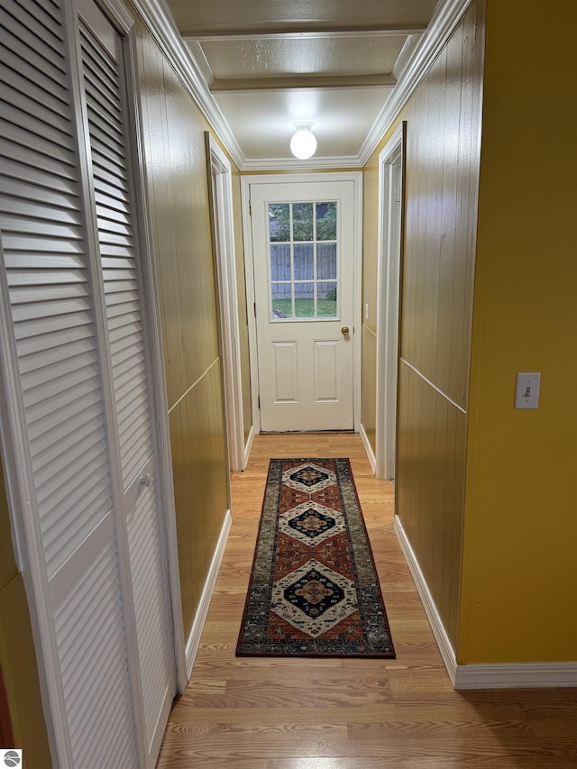 doorway featuring light hardwood / wood-style floors, crown molding, and wood walls