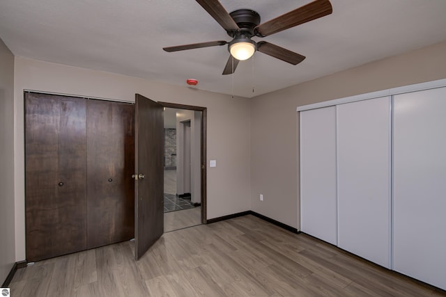 unfurnished bedroom with ceiling fan, light hardwood / wood-style floors, and two closets