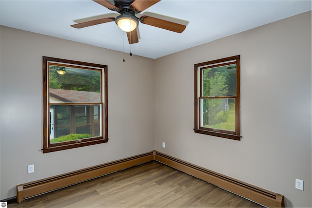 spare room featuring light hardwood / wood-style flooring, ceiling fan, and a baseboard heating unit