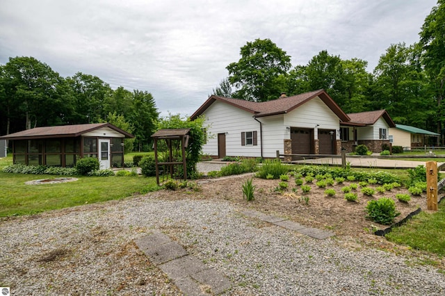 view of front facade featuring a front yard, a garage, and a sunroom