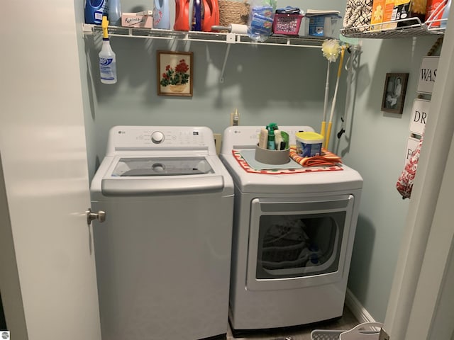 laundry area with laundry area, washing machine and clothes dryer, and baseboards