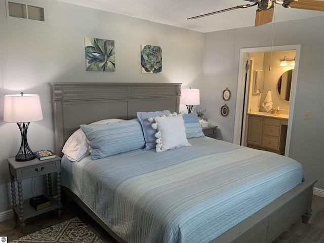 bedroom featuring visible vents, ensuite bathroom, a ceiling fan, wood finished floors, and baseboards