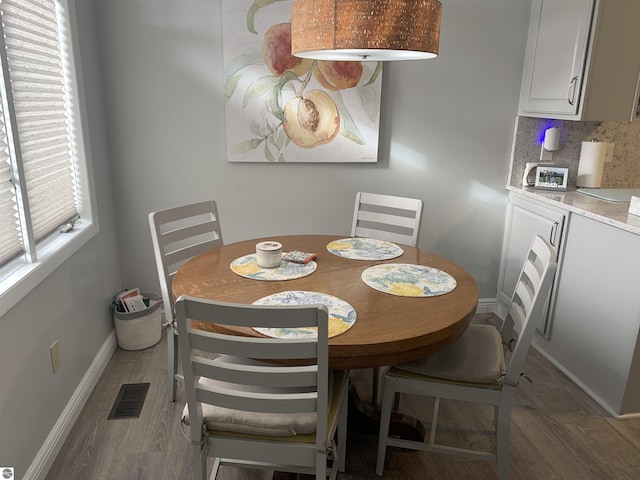 dining room featuring light wood-style floors, visible vents, and baseboards