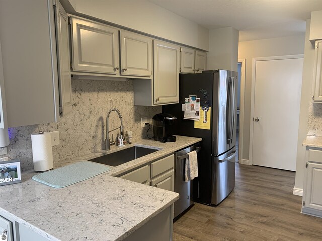 kitchen with wood finished floors, appliances with stainless steel finishes, backsplash, and a sink