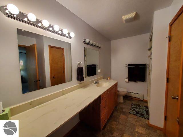 bathroom featuring baseboard heating, vanity, and toilet