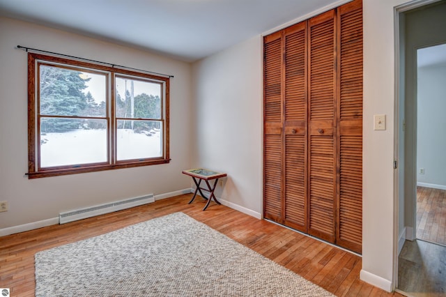 bedroom featuring a closet, a baseboard radiator, and light hardwood / wood-style flooring