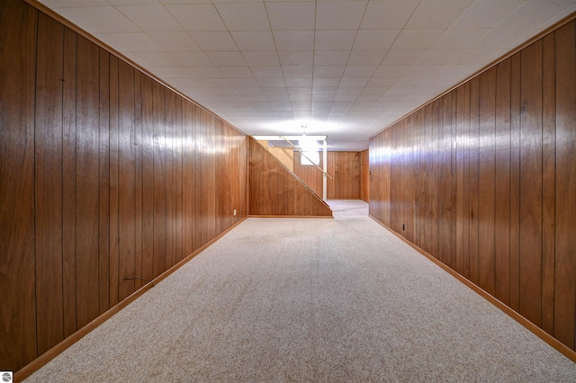 corridor featuring carpet and wood walls