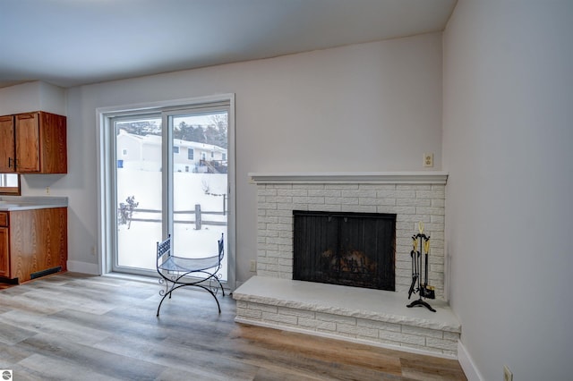 living room with light hardwood / wood-style floors and a brick fireplace