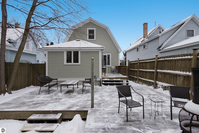 snow covered back of property featuring a deck