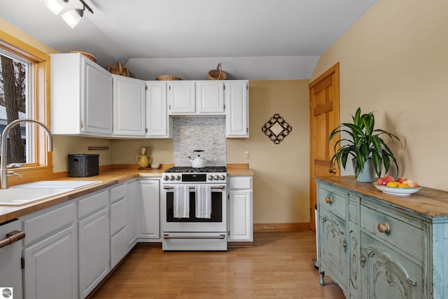 kitchen featuring stainless steel range, white cabinets, and sink