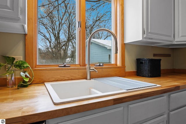 details featuring white cabinets, wood counters, and sink