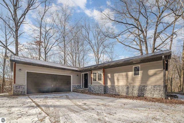 8355 Chippewa Trl, Mount Pleasant, MI 48858 - view of front of house with driveway, stone siding, and a garage