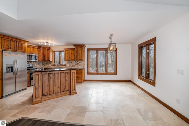 kitchen featuring pendant lighting, appliances with stainless steel finishes, a kitchen island, sink, and backsplash