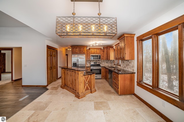 kitchen with a kitchen bar, stainless steel appliances, a center island, decorative light fixtures, and sink