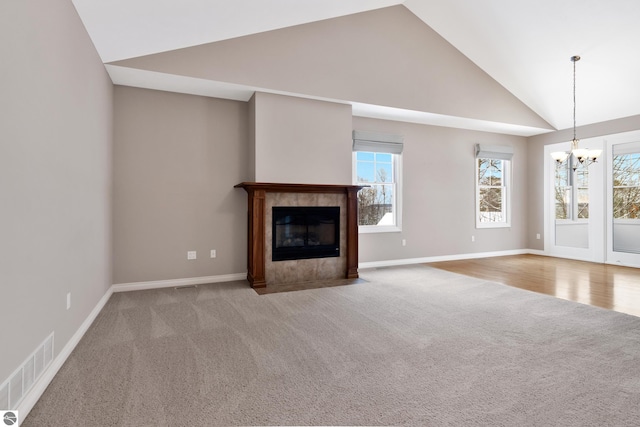 unfurnished living room with a tile fireplace, light colored carpet, and a healthy amount of sunlight