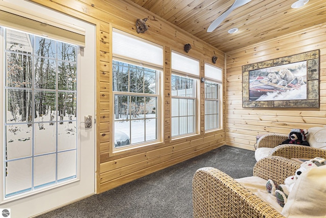 sitting room with ceiling fan, wooden walls, carpet floors, and wooden ceiling