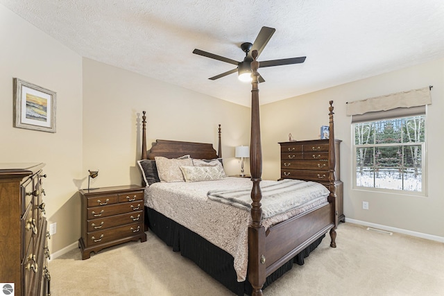 bedroom with ceiling fan, light colored carpet, and a textured ceiling