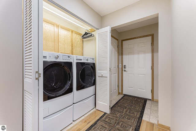 clothes washing area featuring washing machine and dryer and cabinets