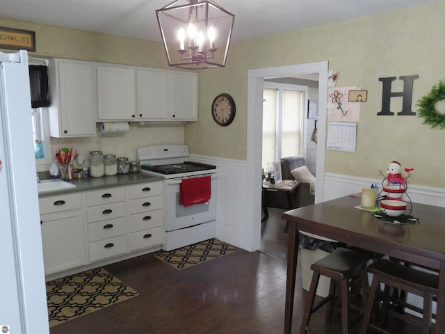 kitchen with white cabinetry, dark hardwood / wood-style flooring, white appliances, and hanging light fixtures