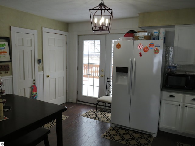 kitchen featuring dark hardwood / wood-style flooring, white refrigerator with ice dispenser, decorative light fixtures, a chandelier, and white cabinetry