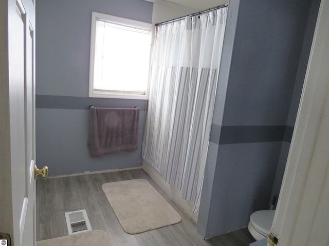 bathroom featuring toilet, wood-type flooring, and a shower with shower curtain