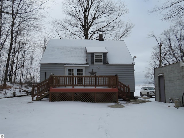 snow covered back of property with a deck and french doors