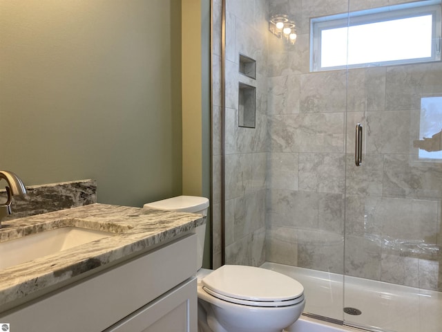 bathroom featuring vanity, toilet, and a shower with shower door