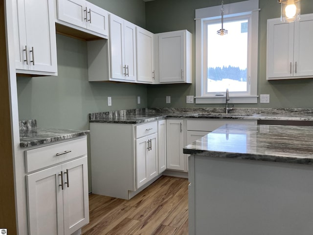 kitchen with white cabinets, light hardwood / wood-style floors, and sink